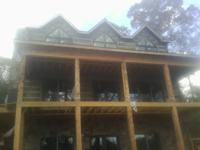 Dormers and porch framing on a large log home under construction — Roof Coating work by our crew in Sun Prairie