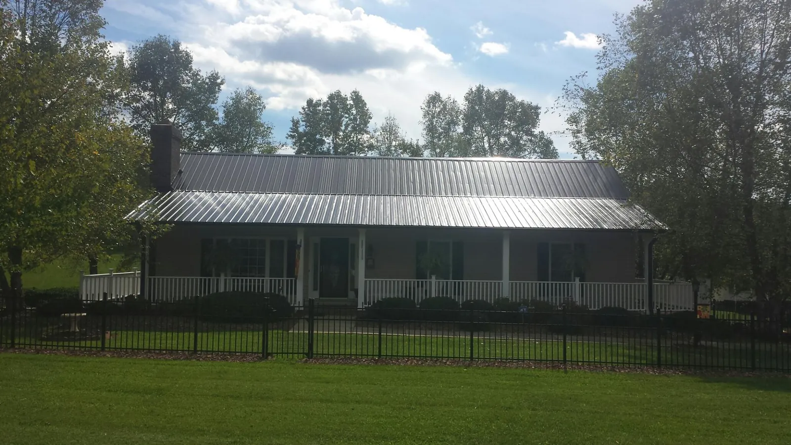 Gray metal roof on a brick ranch with a full width front porch — Gutter Guard Installation work by our crew in Sun Prairie
