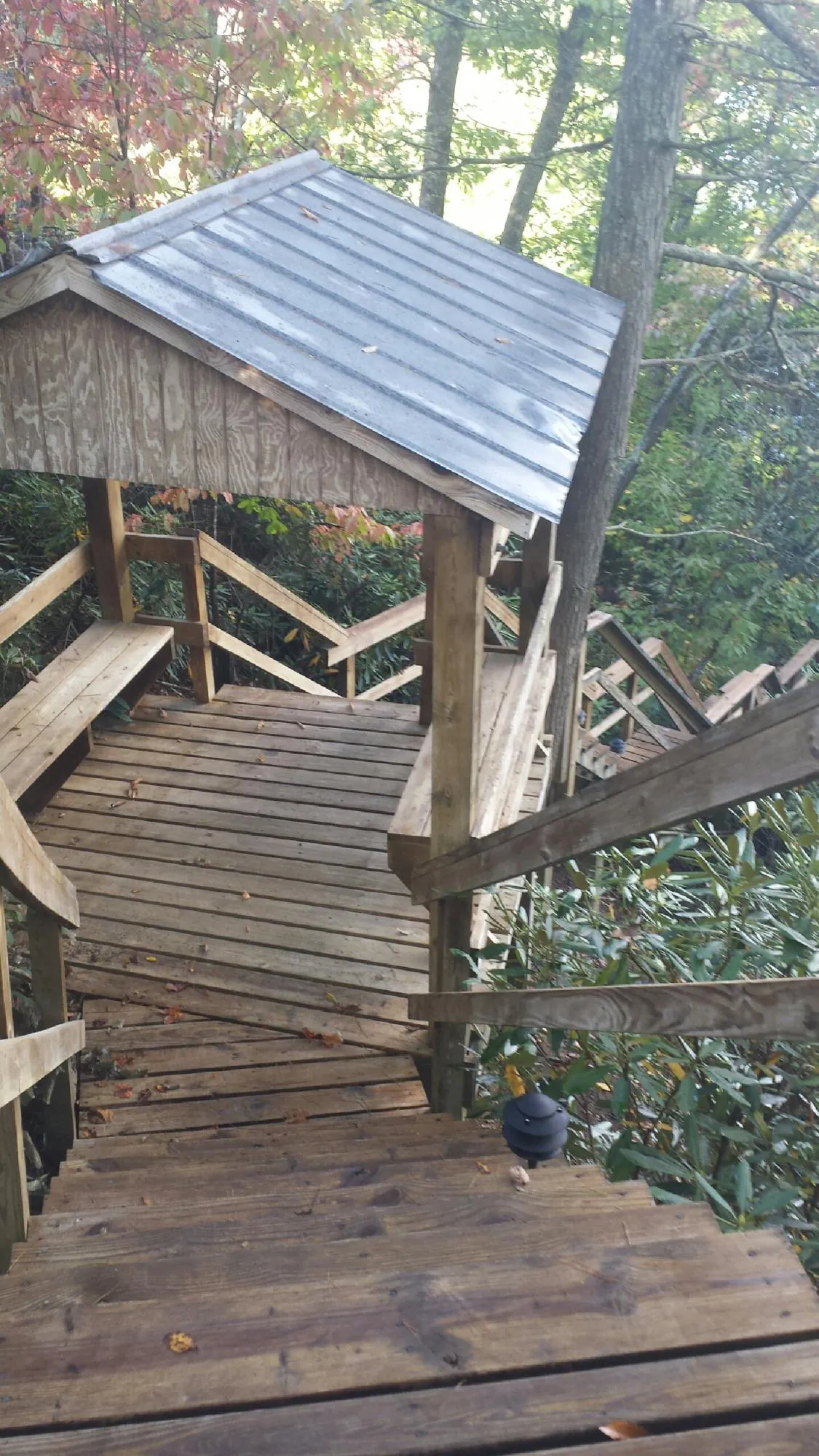 Metal roofed shelter over wooden steps on a wooded walkway — Skylight Repair & Installation work by our crew in Sun Prairie