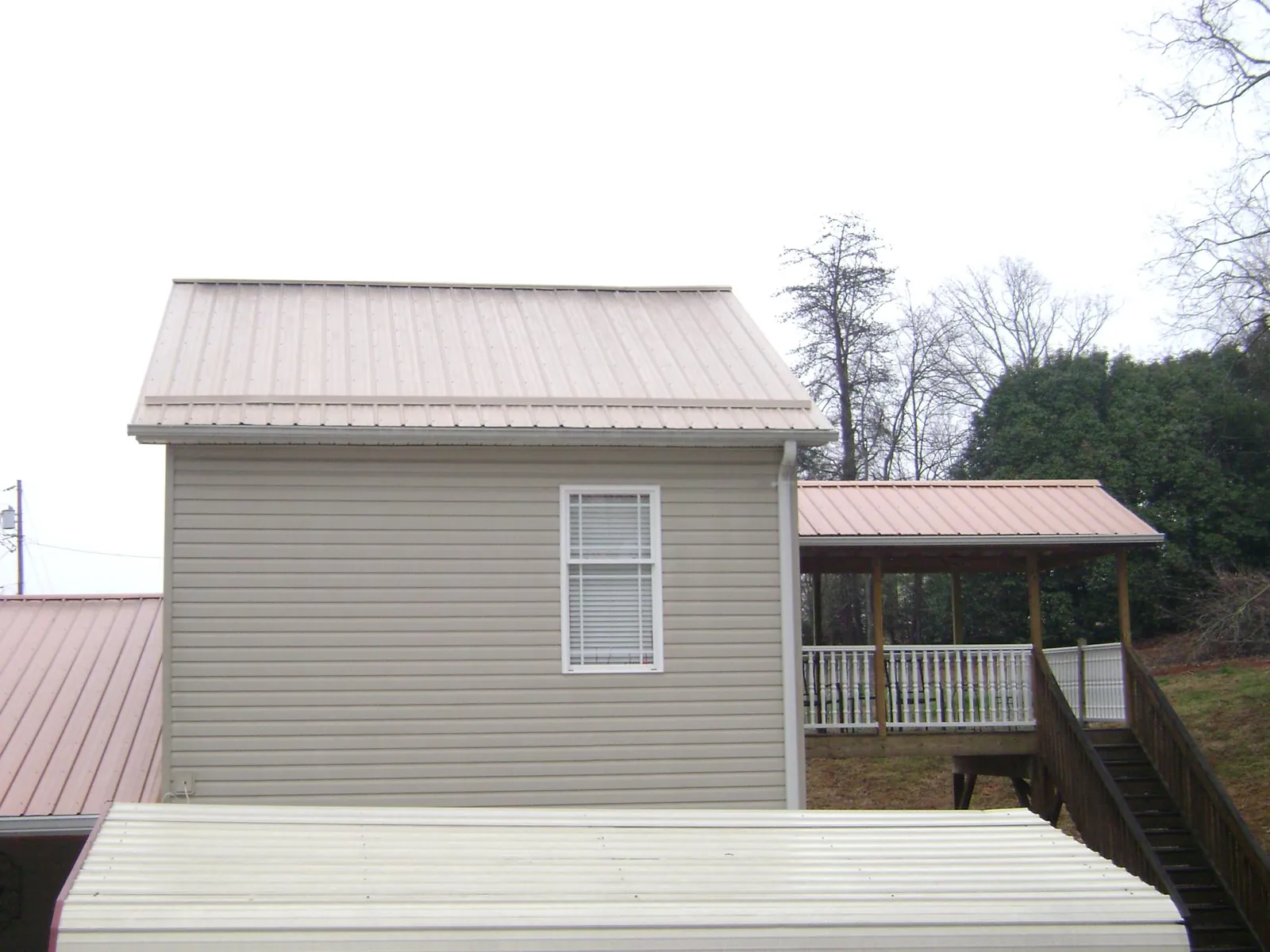 Tan metal roofs on a two story addition and attached porch, from a Roof Replacement job in Sun Prairie
