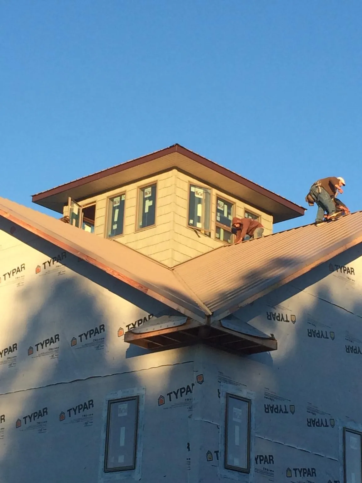 Roofers working around a rooftop cupola on a new metal roof at sunset — Roof Waterproofing in Sun Prairie by Roofing Brothers